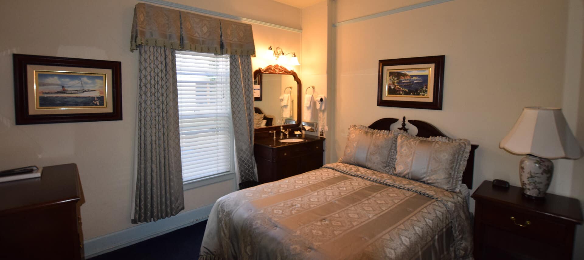 Bedroom with Queen bed, large window and antique dresser with mirror.